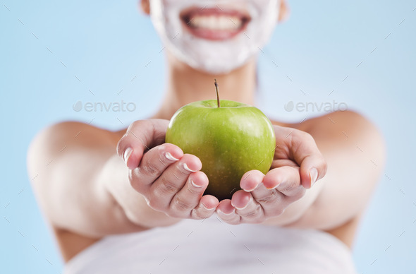 Beautiful young mixed race woman wearing a face mask peel and posing with an apple isolated in stud