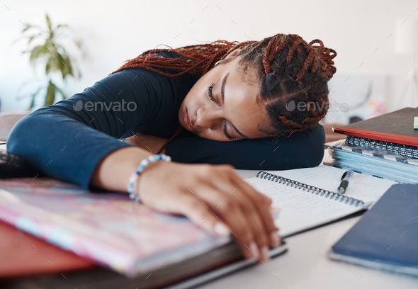 Tired student sleeping at her desk while studying for university or college exams and test. Burnout