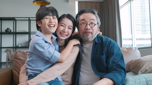 Portrait of happy Asian family spending time together on sofa in living room.