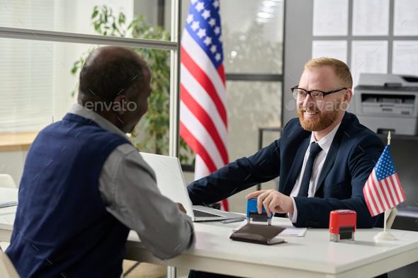 Friendly smiling worker consulting senior man in US immigration office