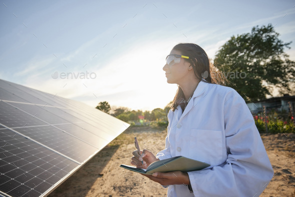 Woman working in solar energy, writing research on solar panels and studying sustainability of clea