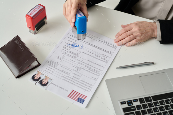 Worker putting approved stamp on visa application