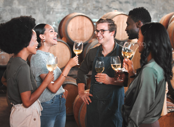 Group of friends wine tasting at a distillery or cellar drinking glasses and enjoying the tour toge