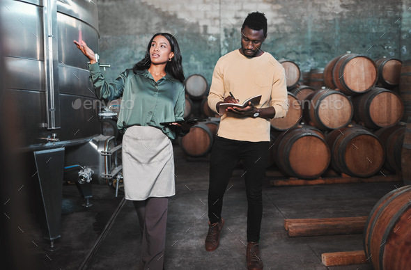 Man, woman and winemaker giving tour to new employee learning logistics in a winery or wood barrel