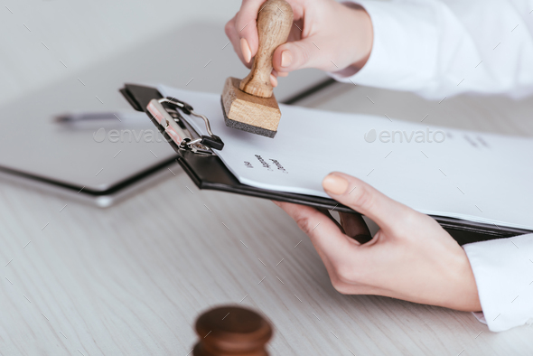selective focus of woman holding clipboard with document and stamp in hands
