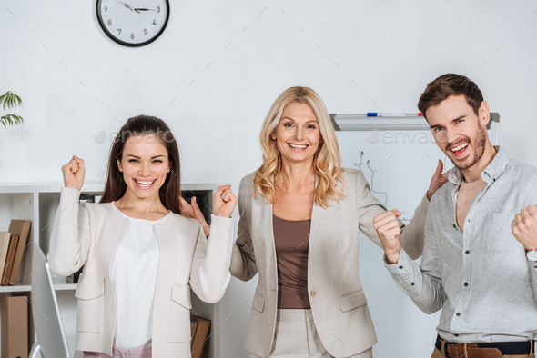 cheerful professional business colleagues shaking fists and smiling at camera in office