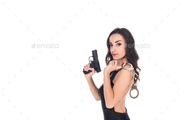 beautiful security agent in black dress holding gun and handcuffs, isolated on white