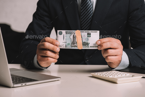 cropped shot of businessman holding russian rubles banknote with medical patch