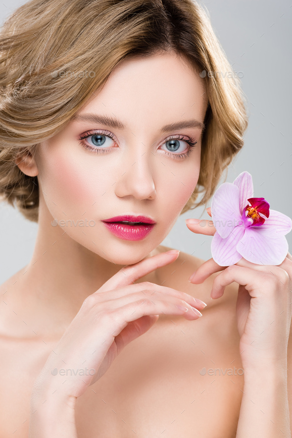 young nude tender woman with purple orchid on hand isolated on grey