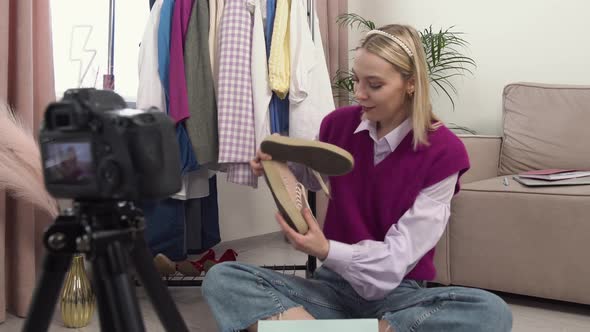 A Woman Sitting Takes Out a Gift From a Bag of Sneakers in Front of the Camera