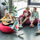 smiling group of friends sitting on bean bag chairs and playing guitar - PhotoDune Item for Sale