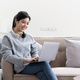 photo of young asian woman happy positive smile sit couch look browse laptop computer indoors - PhotoDune Item for Sale