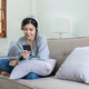 Asian woman listen music with mobile phone and headphones. Calm home weekend, relax while sit on - PhotoDune Item for Sale