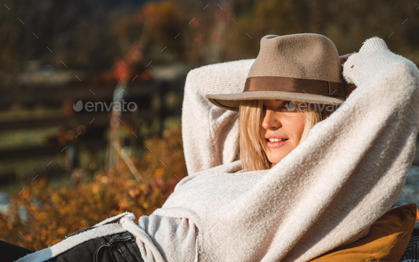 Beautiful girl in cowboy hat relaxing on home garden patio at sunny autumn