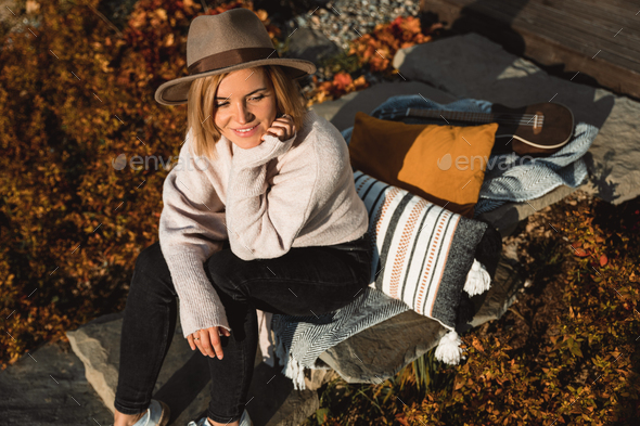 Beautiful girl in cowboy hat relaxing on home garden patio at sunny autumn