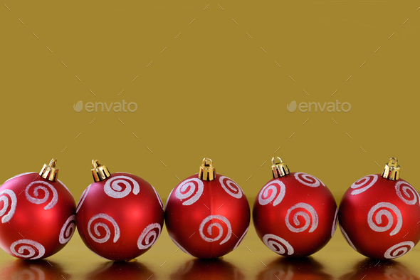 Row of red and white Christmas ornaments decorations on a gold metallic background.