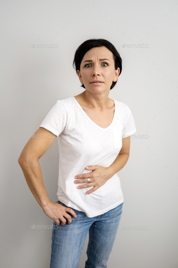 Middle aged woman suffers from abdominal pain. Woman holding her stomach in pain