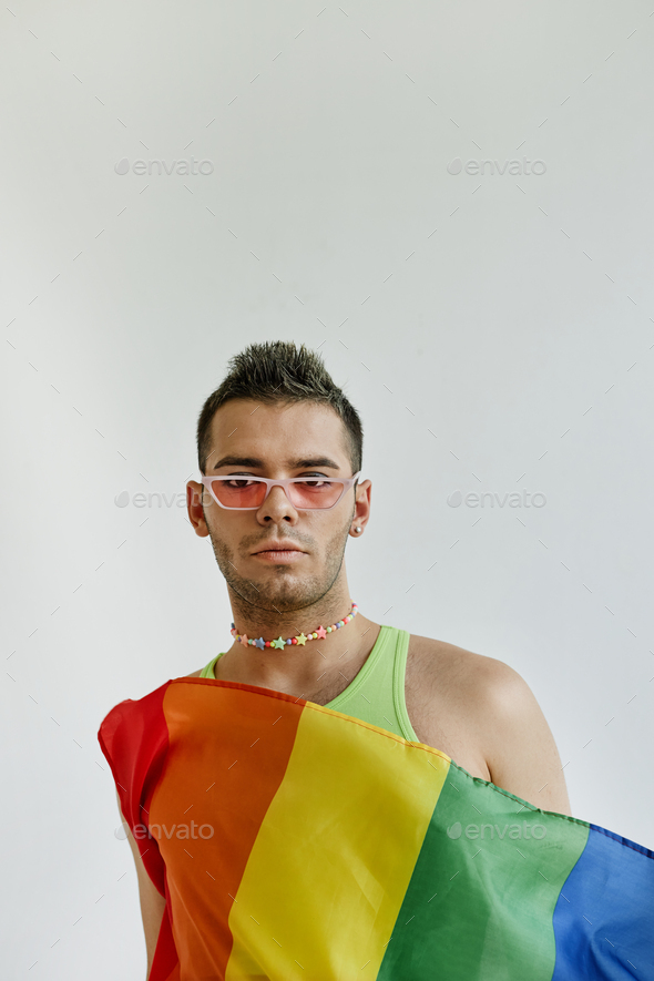 Gay man draped in pride flag against white - Stock Photo - Images