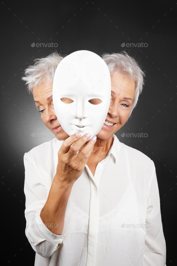 older woman hiding happy and sad face behind mask