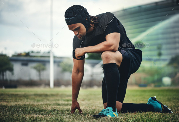 Full length shot of a handsome young rugby player kneeling down on the field during the day