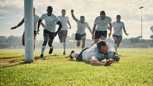 Full length shot of a handsome young rugby player scoring a try while training on a rainy day