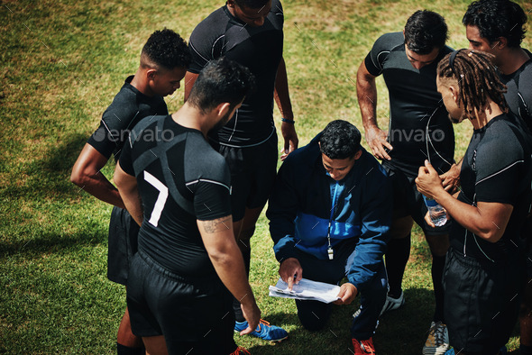High angle shot of a handsome young rugby coach addressing his team on the field during the day