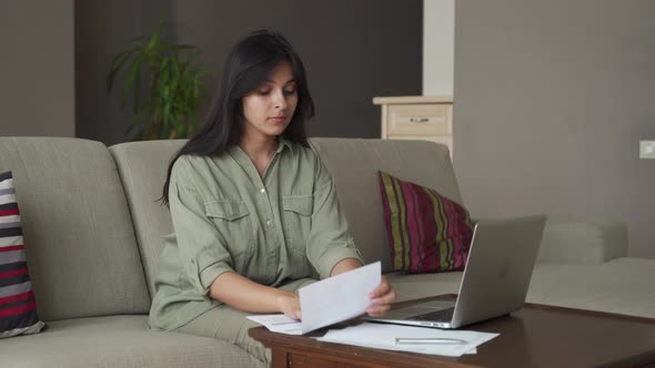Serious Indian Lady Reading Bill Using Computer Making Online Payment at Home alt