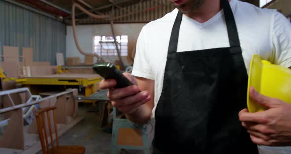Attractive carpenter using his phone and smiling for camera alt