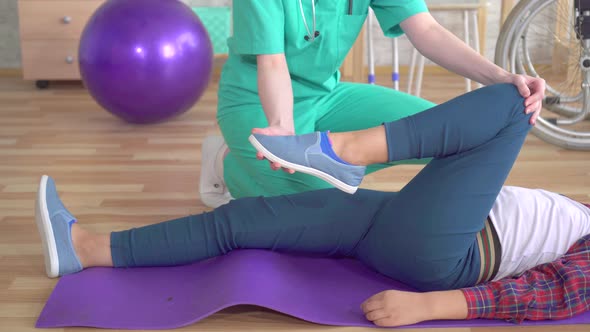 Physiotherapist in the Rehabilitation Center Helps in Warming Up the Legs of a Teenage Girl in alt
