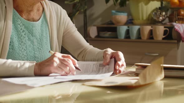 Senior Woman Writing Down on Document