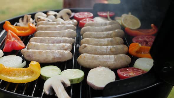 Metal Tongs Put Zucchini and Tomato on the Grill