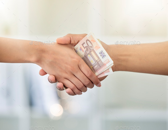 Money exchange, deal or trade handshake of hands giving cash to a banker of a financial advisor. Ha