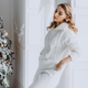Young happy blonde woman in white clothes on the background of a Christmas tree. - PhotoDune Item for Sale