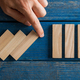 Falling wooden dominos being interrupted by male hand in a conceptual image of crisis management - PhotoDune Item for Sale