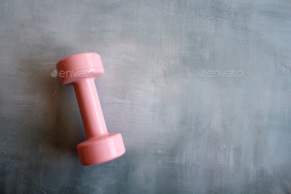 Pink dumbbell on concrete floor with copy space