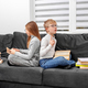 Children read books in eyeglasses sitting on sofa in room. Brother and sister are studying homework. - PhotoDune Item for Sale
