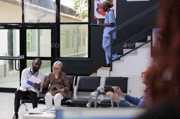 Elderly patient patient looking at papers with medical report while physician explaining medication - Stock Photo - Images