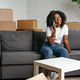 Young african woman with smartphone and boxes moving to new home - PhotoDune Item for Sale