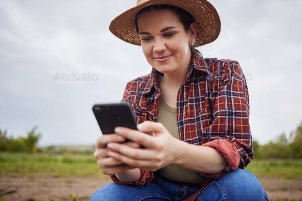 Farmer texting or scrolling on social media on a phone for online sustainability tips relaxing on a