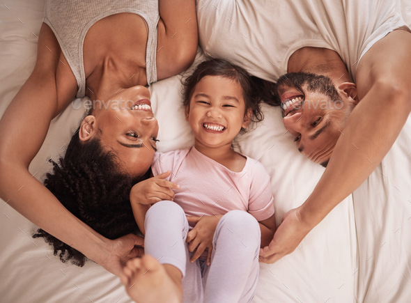 Family, parents and child happy on bed, smile, laugh and bonding on weekend. Mom, dad or couple wit
