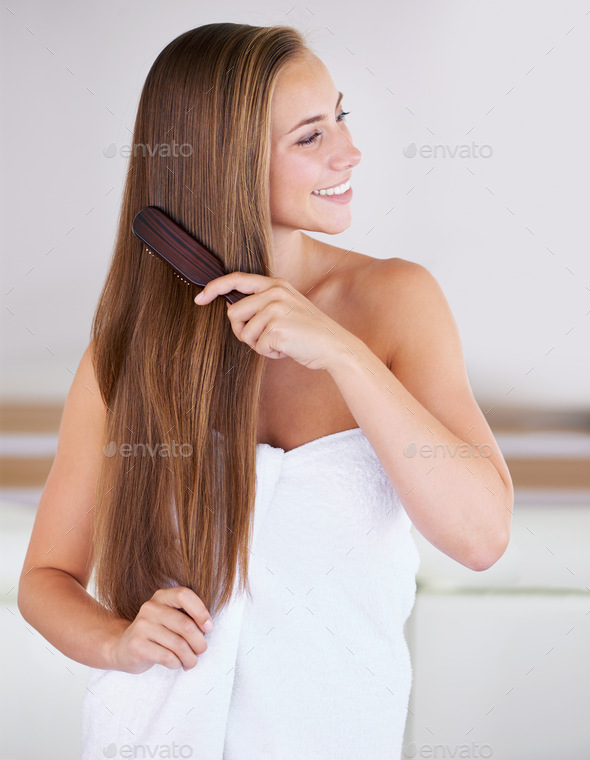 Brushing makes your hair grow faster. A gorgeous brunette woman brushing her healthy long hair.