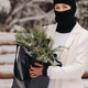 A girl in a white suit and balaclava with a package of Christmas trees in the winter forest on New - PhotoDune Item for Sale