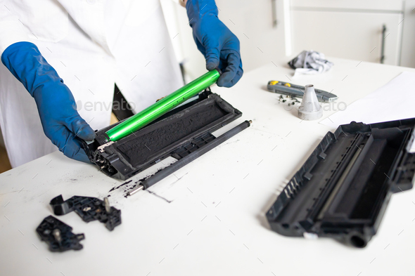 hands repairing laser toner cartridge. worker Laser printer on a workbench.