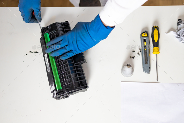 hands repairing laser toner cartridge. worker Laser printer on a workbench.