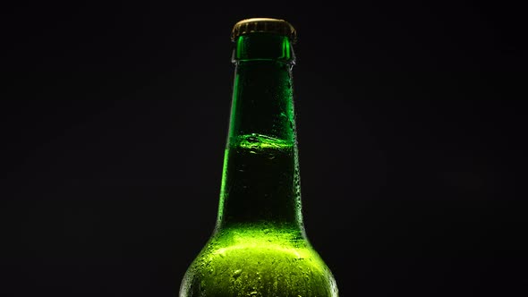 Beer Bottle Rotating Against Dark Background alt