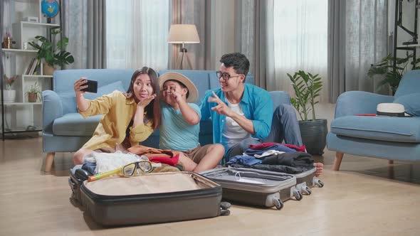 Asian Family Packing Clothes In A Suitcase And Selfie For A New Journey. Luggage For Travel Holidays alt
