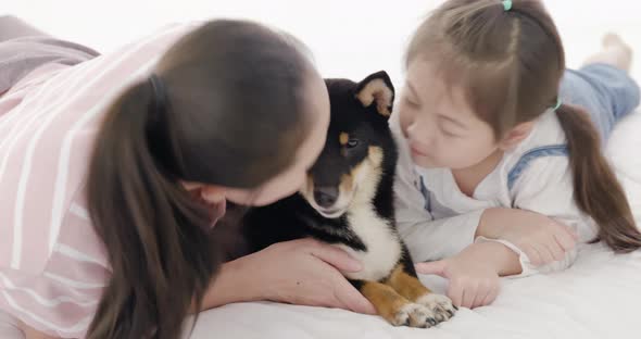 Mother and daughter playing with black dog on bed (10)