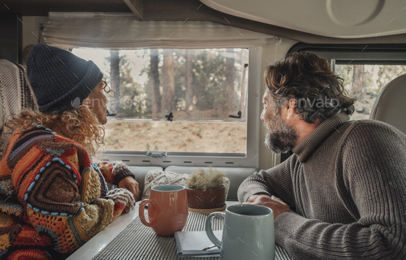 Young mature couple enjoy time inside camper van in van life lifestyle vacation. Travel people