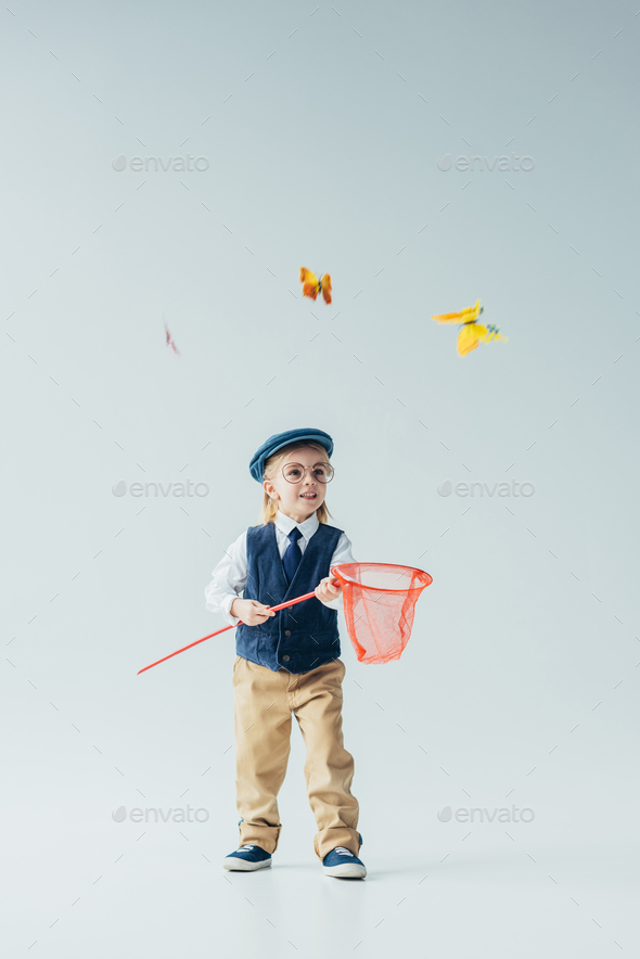 cute kid in retro vest and cap catching butterflies with butterfly net