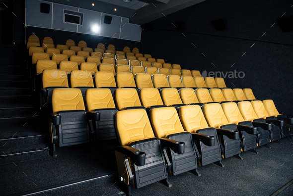 dark cinema hall with comfortable empty seats with cup holders